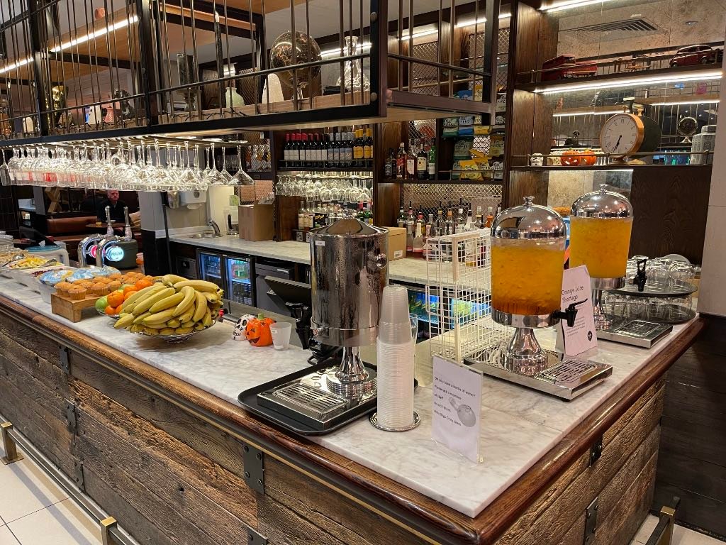 Breakfast bar with juices, water, fruits, muffins, etc.